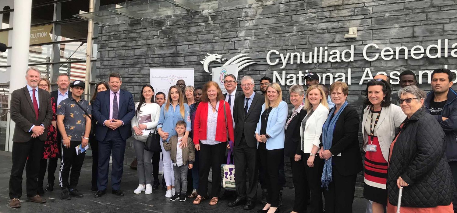 A photograph of the Welsh Refugee Council group outside the Welsh Senedd building.
