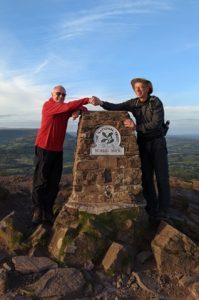 A photo of Harry Iles and a friend at the Skirrid mountain trig point in South Wales.