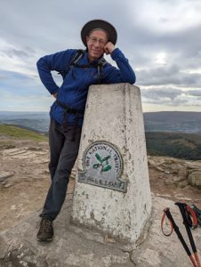 Harry Iles leans on the Sugar Loaf Mountain trig point in South Wales. 