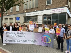 A photograph of a group of people from the Welsh Refugee Council protesting against the UK Rwanda policy.
