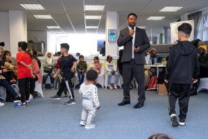 A man speaks to a group of people at a Mental Health Day and Black History Month event.