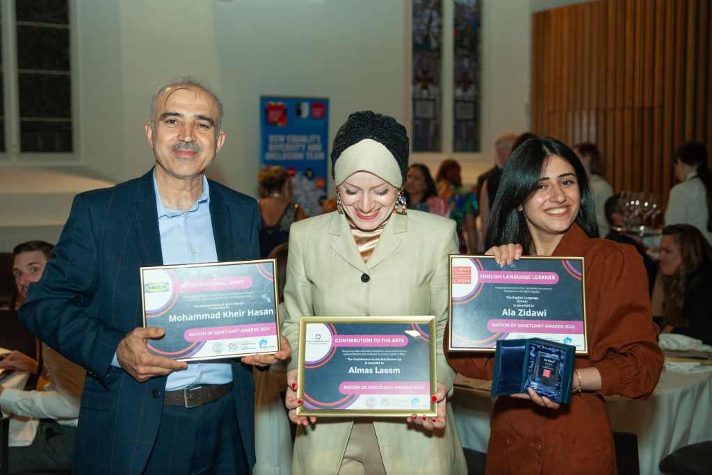 Three award nominees smiling and holding their certificates. 