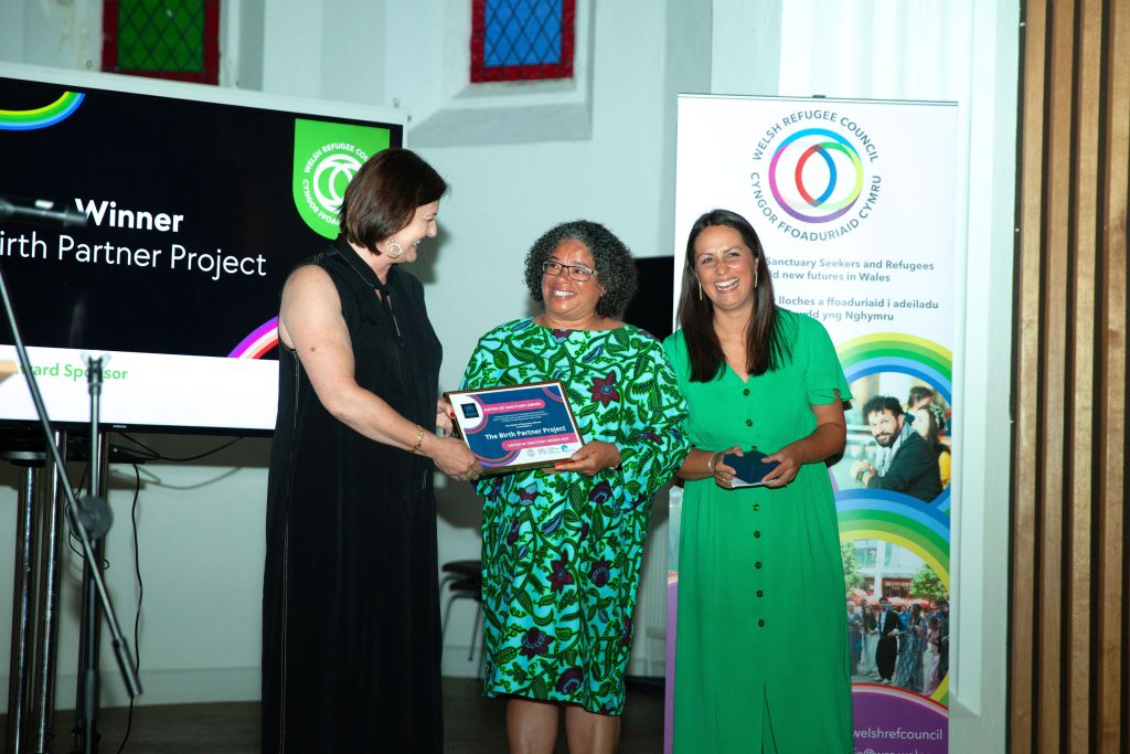 Two women presented with a certificate on stage. 