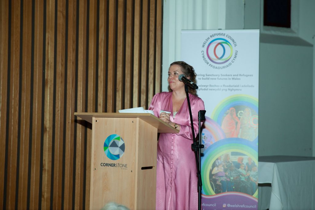 Woman speaking into a microphone on stage. 