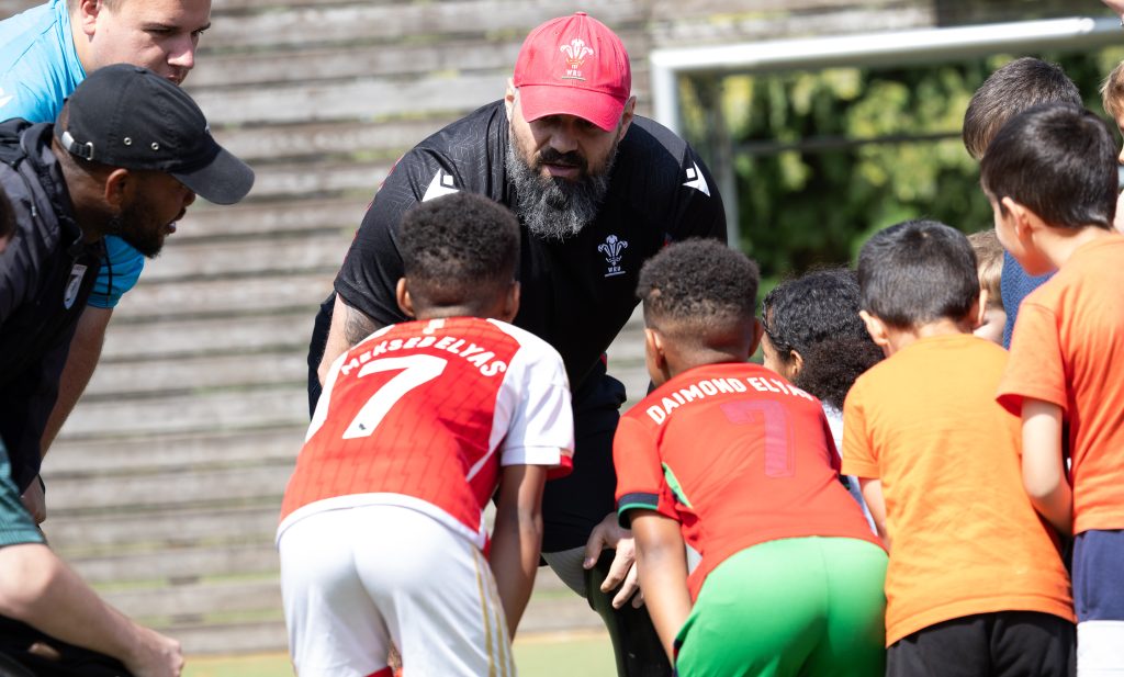 Sanctuary seeking children listening to rugby coach in a huddle. 