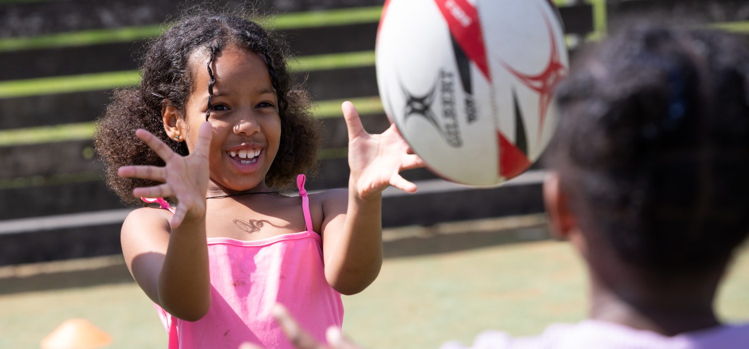 Girl throw a rugby ball to her friend at Play Project.