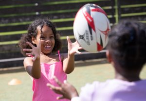 Girl throw a rugby ball to her friend at Play Project.