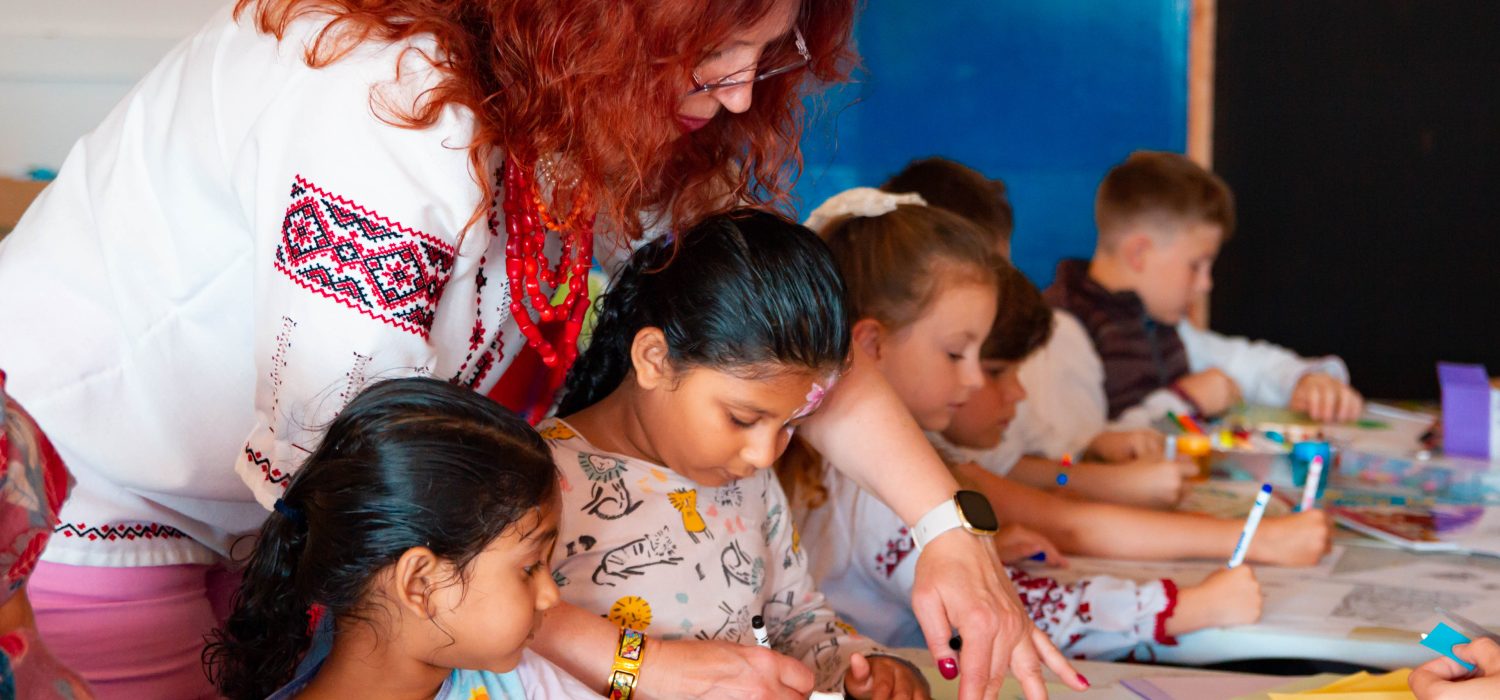 Woman helping children during an art workshop.