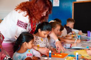 Woman helping children during an art workshop.