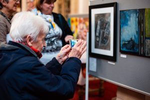 Woman taking a photo of artwork. 