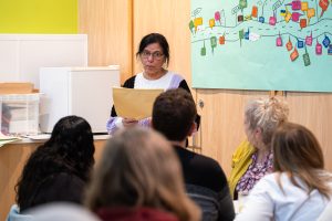 Woman presenting information to a room of people.