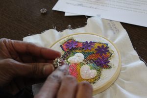 Hands stitching a migration story.