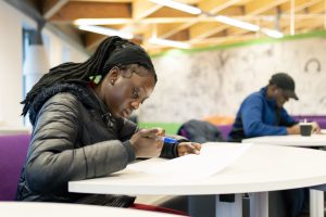 Woman writing notes at a community workshop in Cardiff Central Library. 