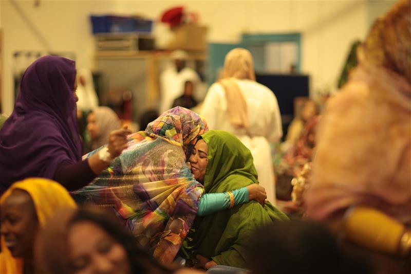 Two women hug at an event with Welsh Refugee Council.
