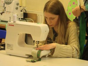 Woman operating a sewing machine in a Shaping Nations workshop.