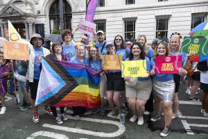 Welsh Refugee Council team hold flags and banners at pride march. 