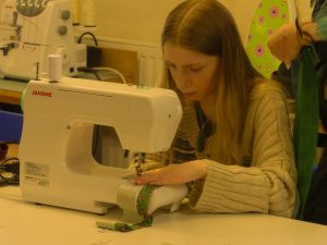 Woman working at a sewing machine in a Welsh Refugee Council craft workshop.