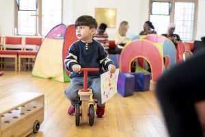 Child at Play Project riding a small wooden tricycle.