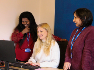 Welsh Refugee Council team smiling and working together at a laptop.
