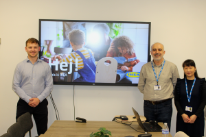 Three members of the Employability and Education team smiling in front of a white board.   